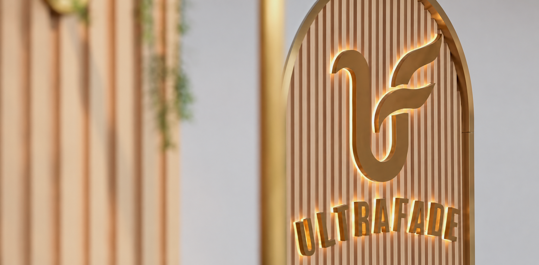 The complete illuminated gold Ultrafade logo on the salon timber feature wall